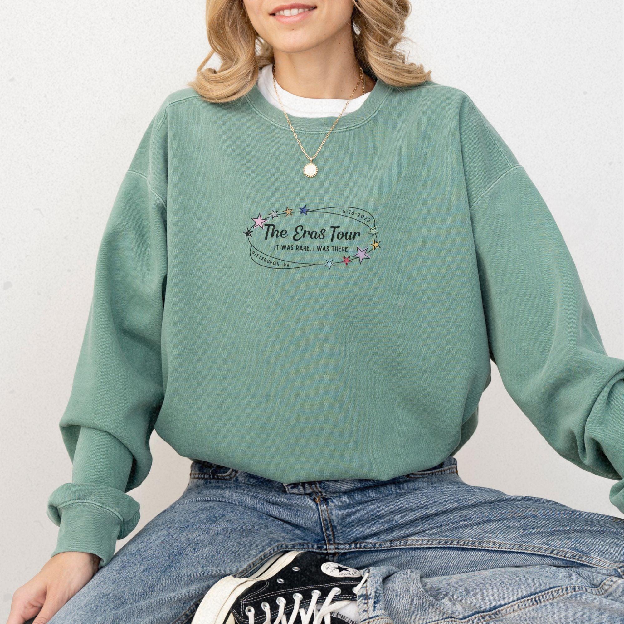 a woman wearing a green sweatshirt and jeans