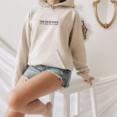 a woman in a white hoodie is leaning on a stool