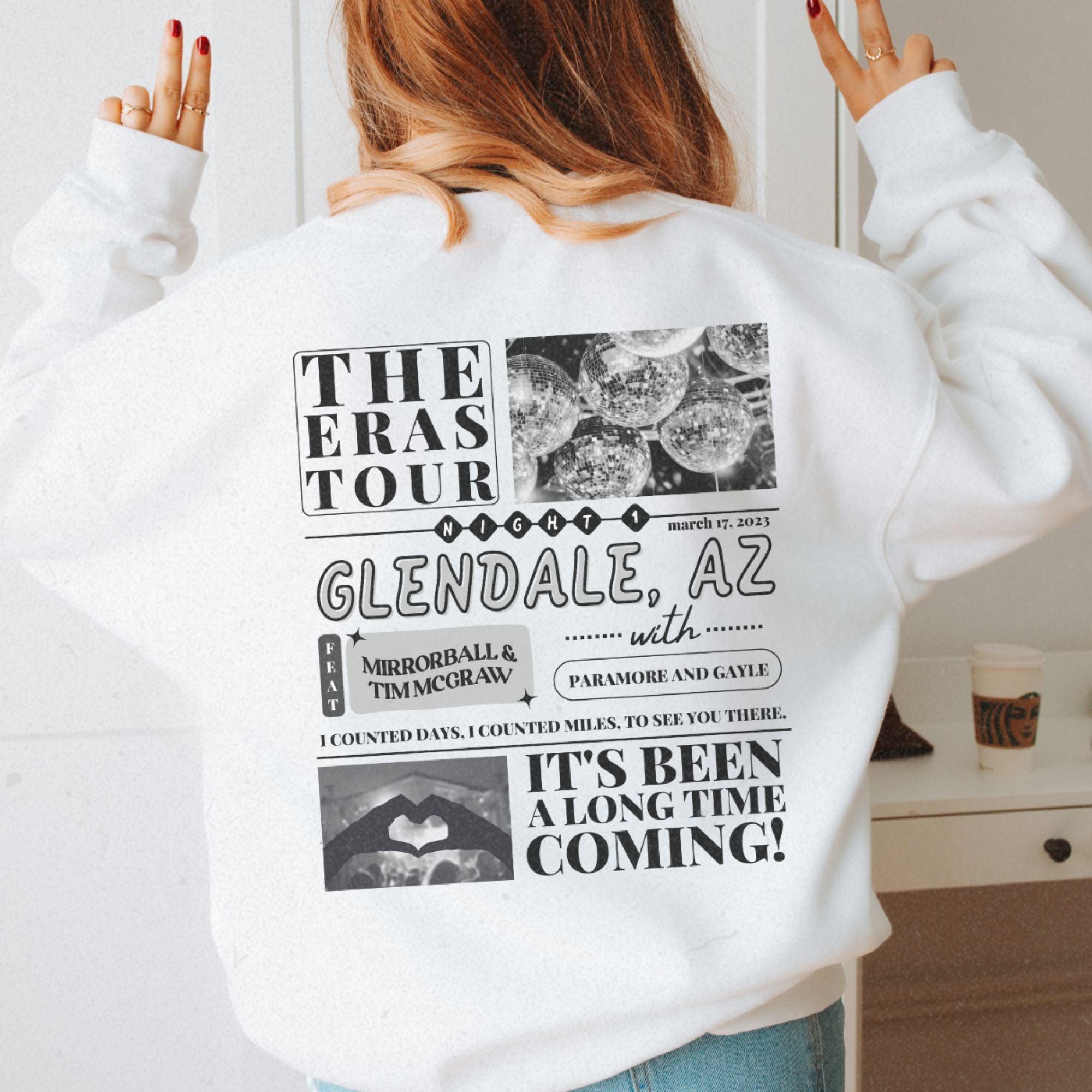 a woman wearing a white sweatshirt with the words the eras tour, gendale