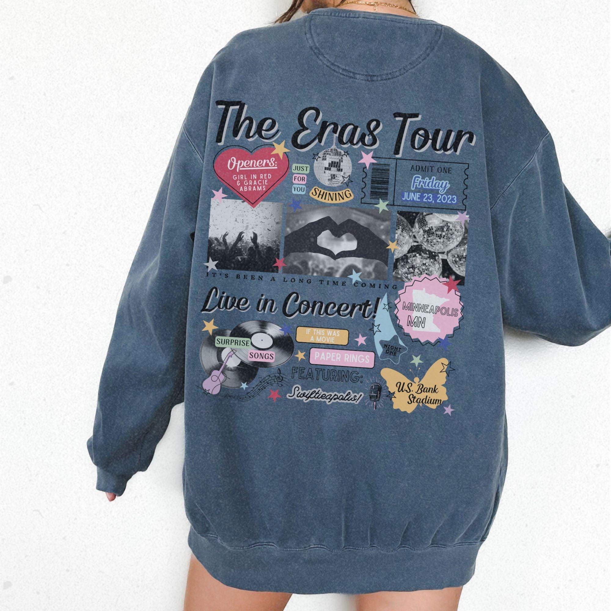 a woman wearing a blue sweatshirt with the words the eras tour on it