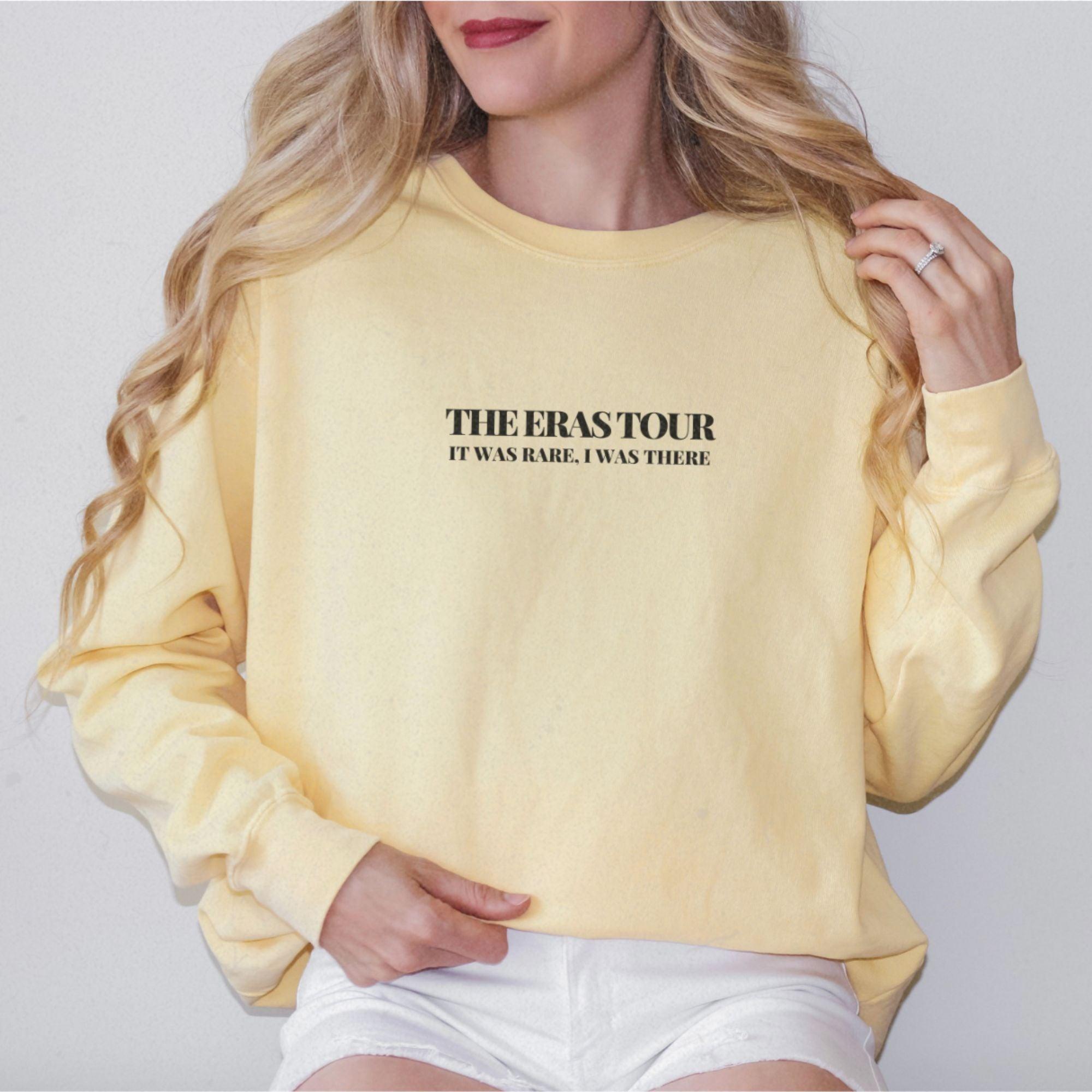 a woman wearing a yellow sweatshirt with the words theaststorr on it