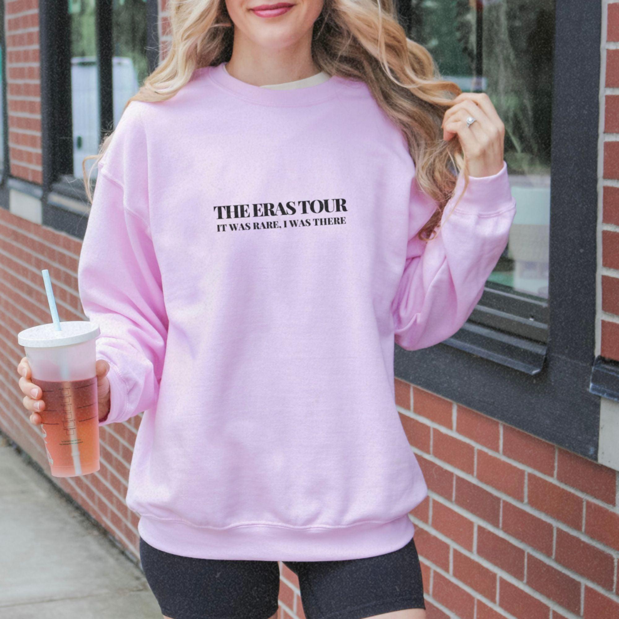 a woman in a pink sweatshirt holding a drink