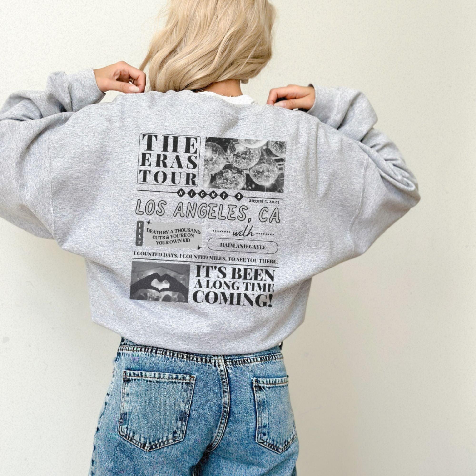 a woman wearing a sweatshirt with the words the eras tour on it