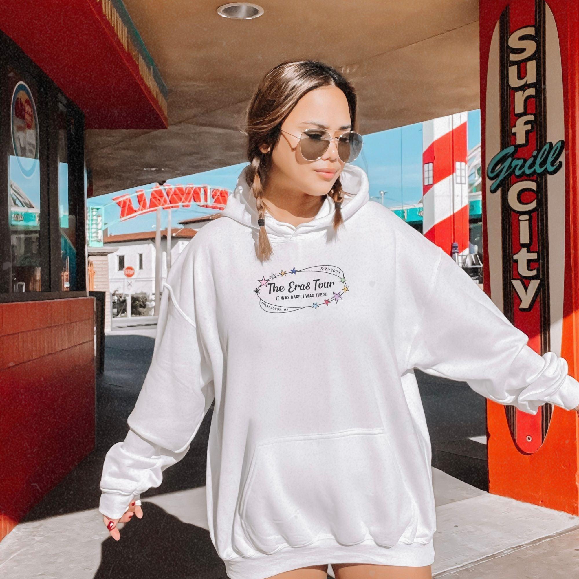 a woman walking down a sidewalk wearing a white sweatshirt