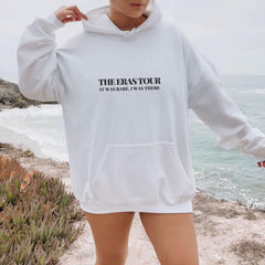 a woman standing on a beach wearing a white sweatshirt