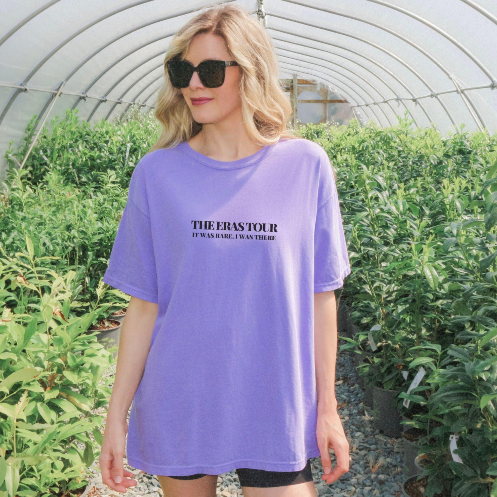 a woman standing in a greenhouse wearing a purple shirt