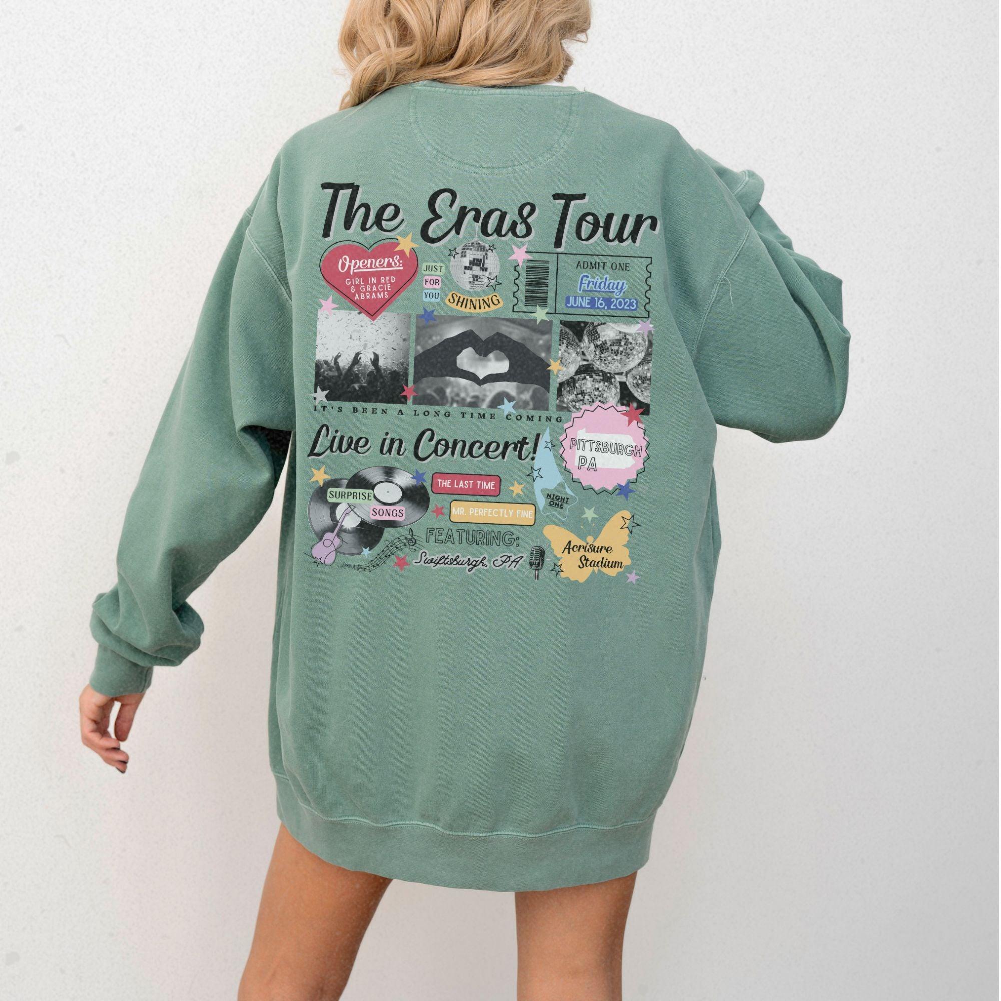 a woman wearing a green sweatshirt with the words the eras tour on it