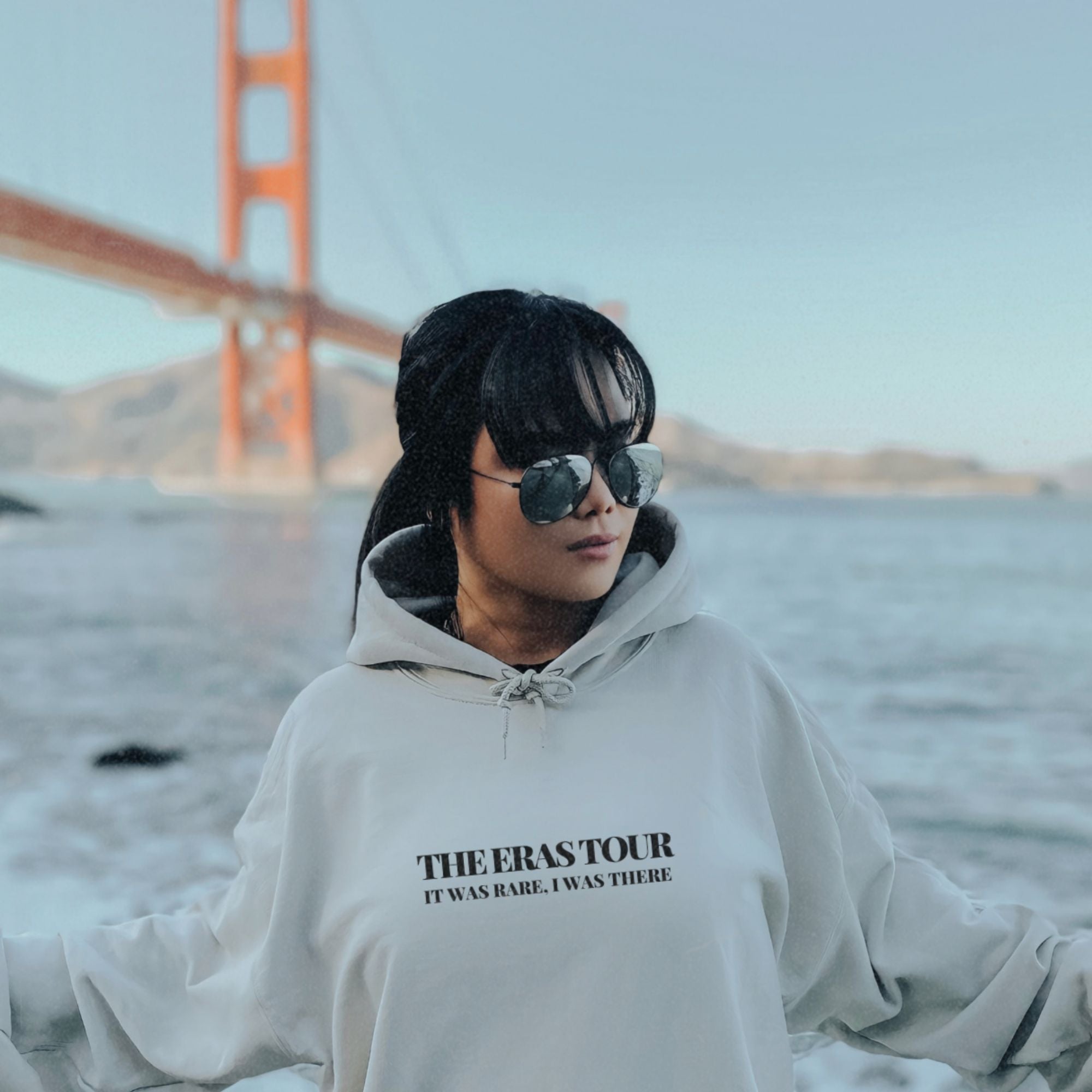 a woman wearing a sweatshirt with the golden gate bridge in the background