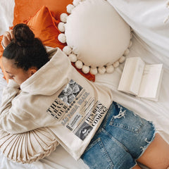 a woman laying on top of a bed next to a book