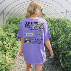 a woman in a purple shirt is walking through a greenhouse