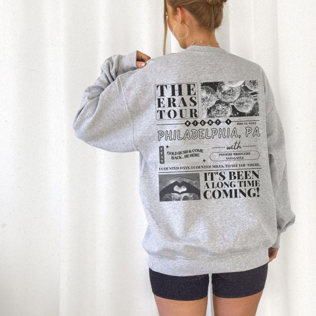 a woman wearing a grey sweatshirt with the words the east tour printed on it