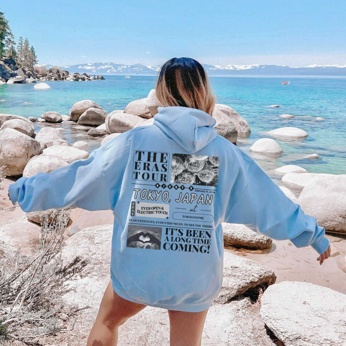 a woman in a blue hoodie standing on a beach